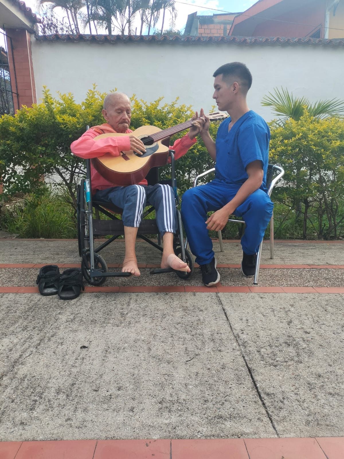 Residente tocando guitarra junto a su cuidador